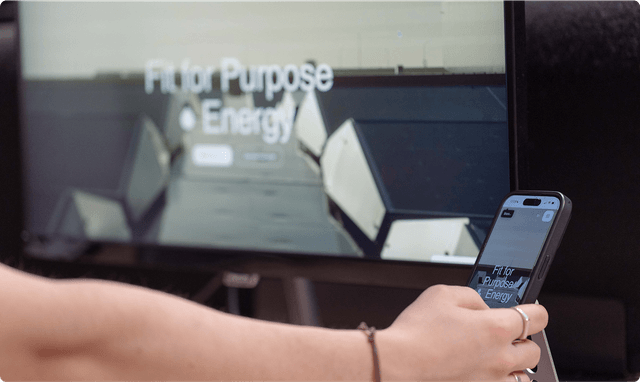 Brand collateral Person holding a smartphone in front of a screen displaying "Fit for Purpose Energy" with geometric shapes in the background.